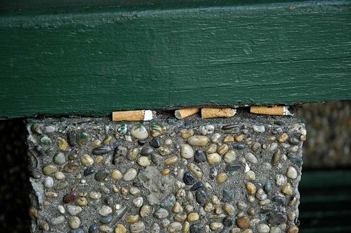 Cigarette butts jammed in public bench