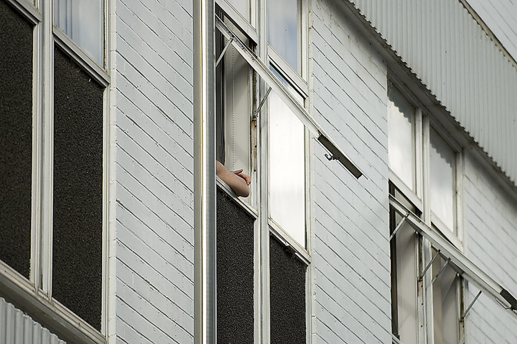 Bland, grey cement wall, with arm resting on window sill